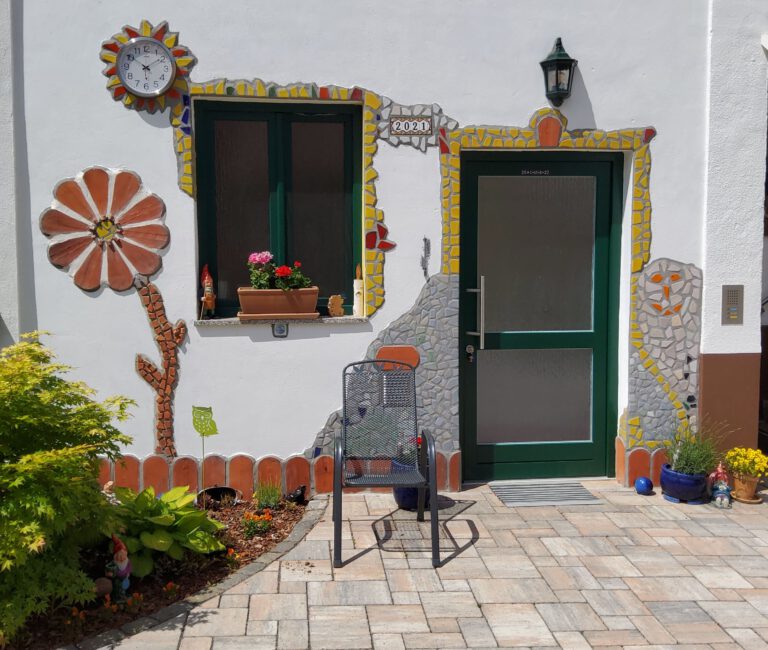 Bunter Eingangsbereich mit dekorierter Hausfassade und Gartenterrasse